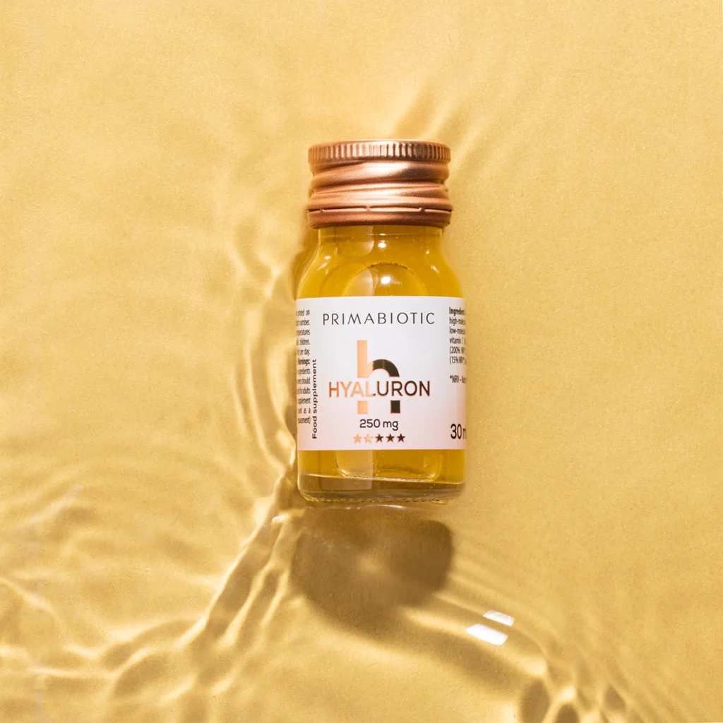 Botellita de ácido hialurónico Primabiotic sobre fondo dorado con agua