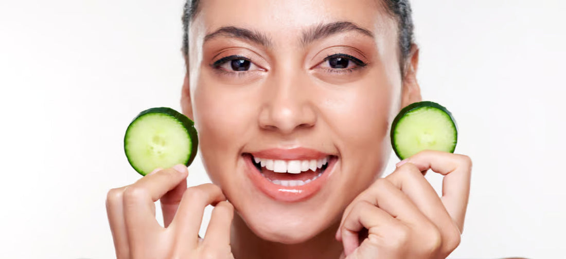 La cara sonriente de una mujer que sostiene rodajas de pepino.