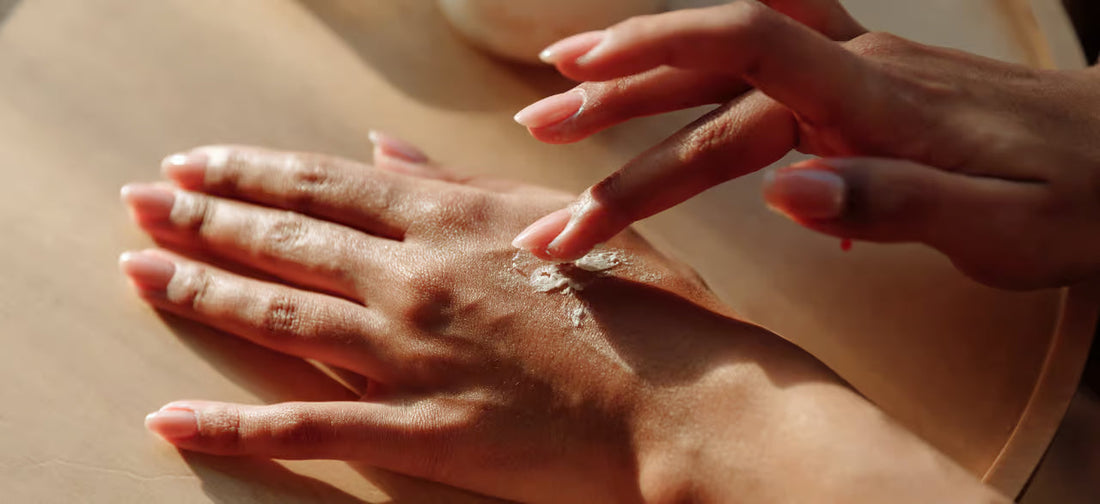 Mano femenina aplica crema hidratante en la piel bajo la luz natural