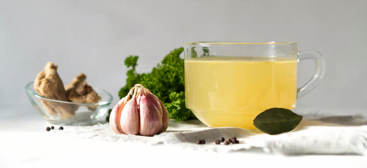 Caldo de colágeno en una taza, y al lado ajo y otras especias