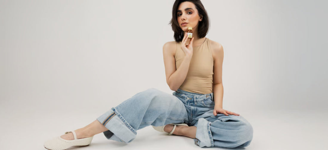 Una mujer con una tez radiante y un cabello abundante con un frasco de colágeno Primabiotic.