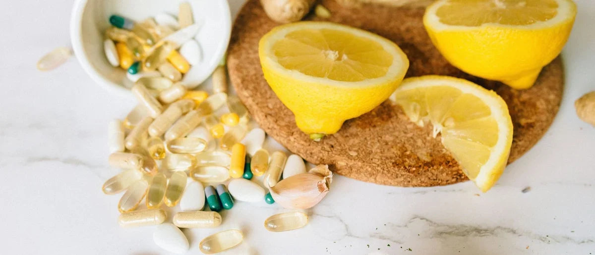 Suplementos y vitaminas para las defensas, colocados sobre una encimera junto a un limón cortado.