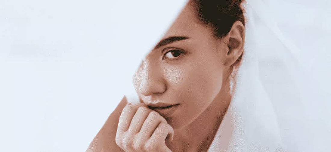 Rostro de mujer parcialmente cubierto por una tela blanca|