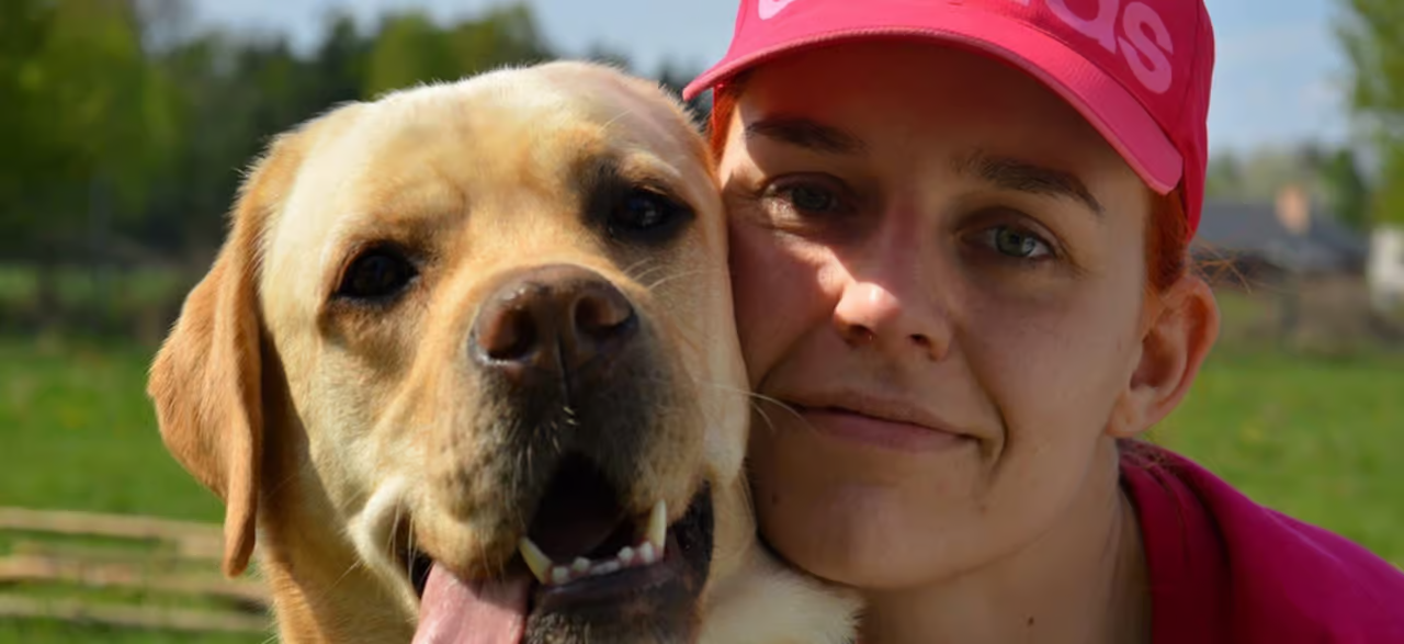 una mujer con gorra y un perro labrador