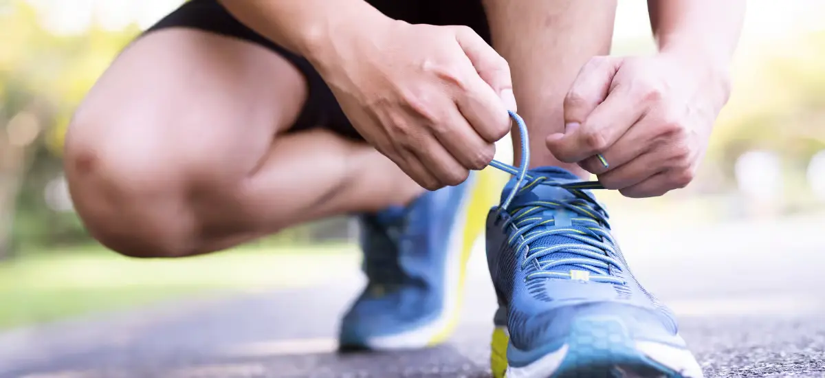 Una persona se pone en cuclillas y se ata las zapatillas de correr